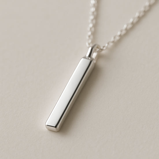 A close‑up of a sleek sterling silver bar pendant hanging on a delicate chain, soft light reflecting off the polished surface. Alt: classic sterling silver bar pendant necklace timeless elegance